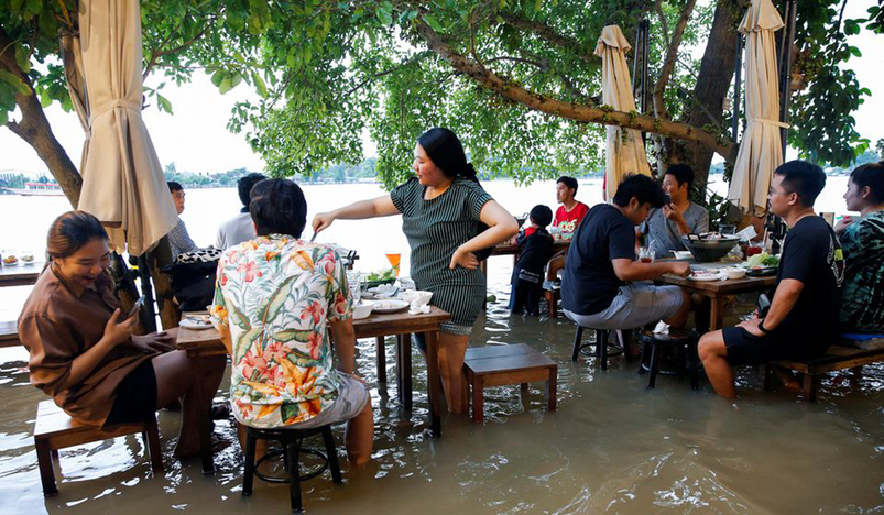 People eat food at a flooded restaurant
